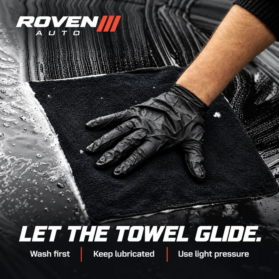 Gloved hand using a lubricated clay towel on vehicle paint